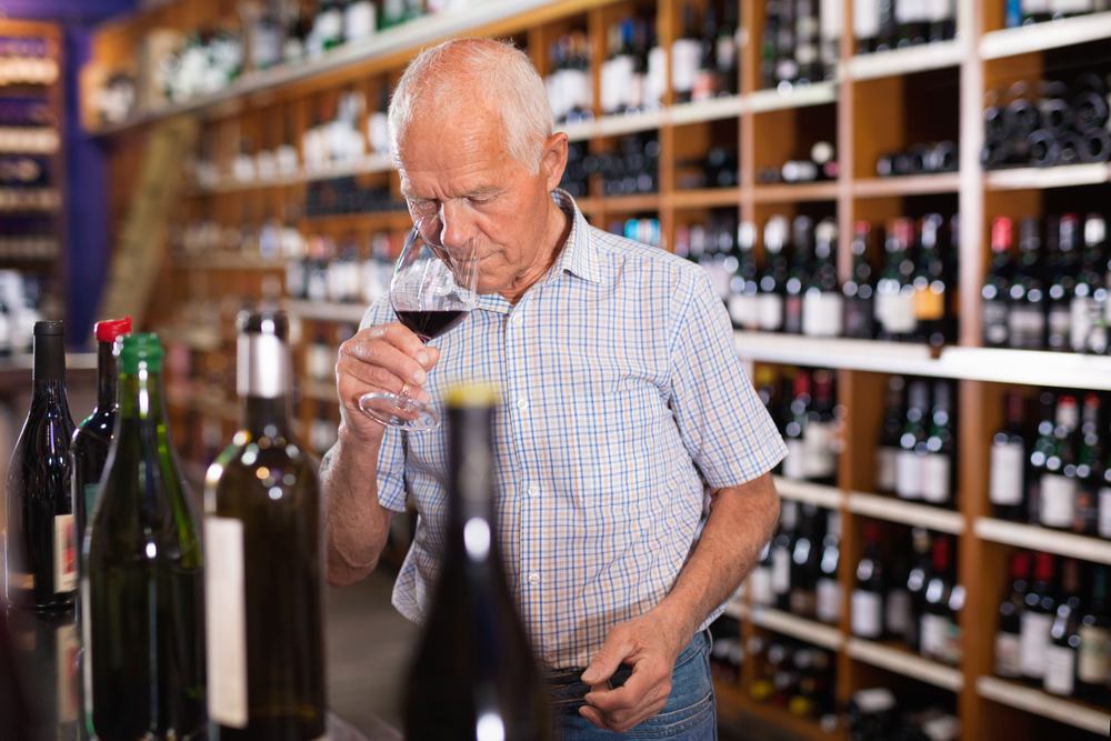 Homem cheirando taça de vinho