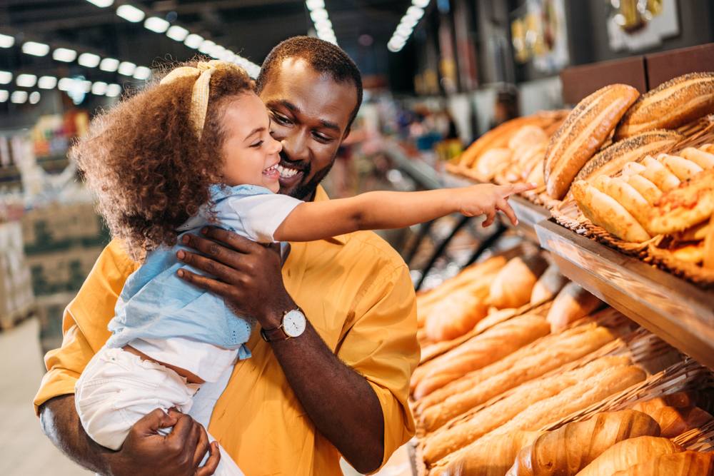 Pai segurando menina com pães ao lado